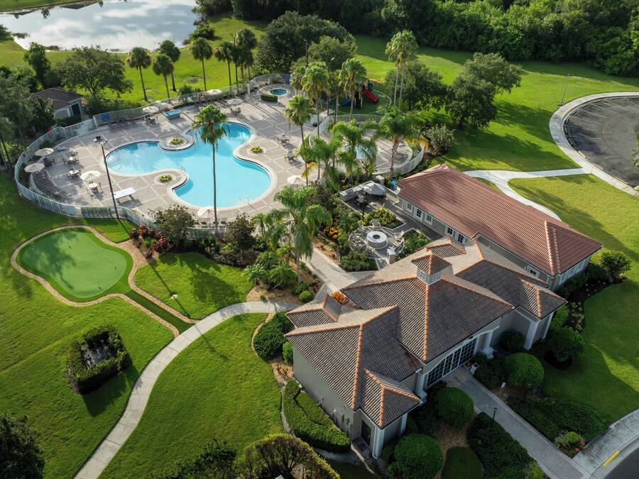 A residential property with a swimming pool, a golf course, and a large house with a tiled roof.