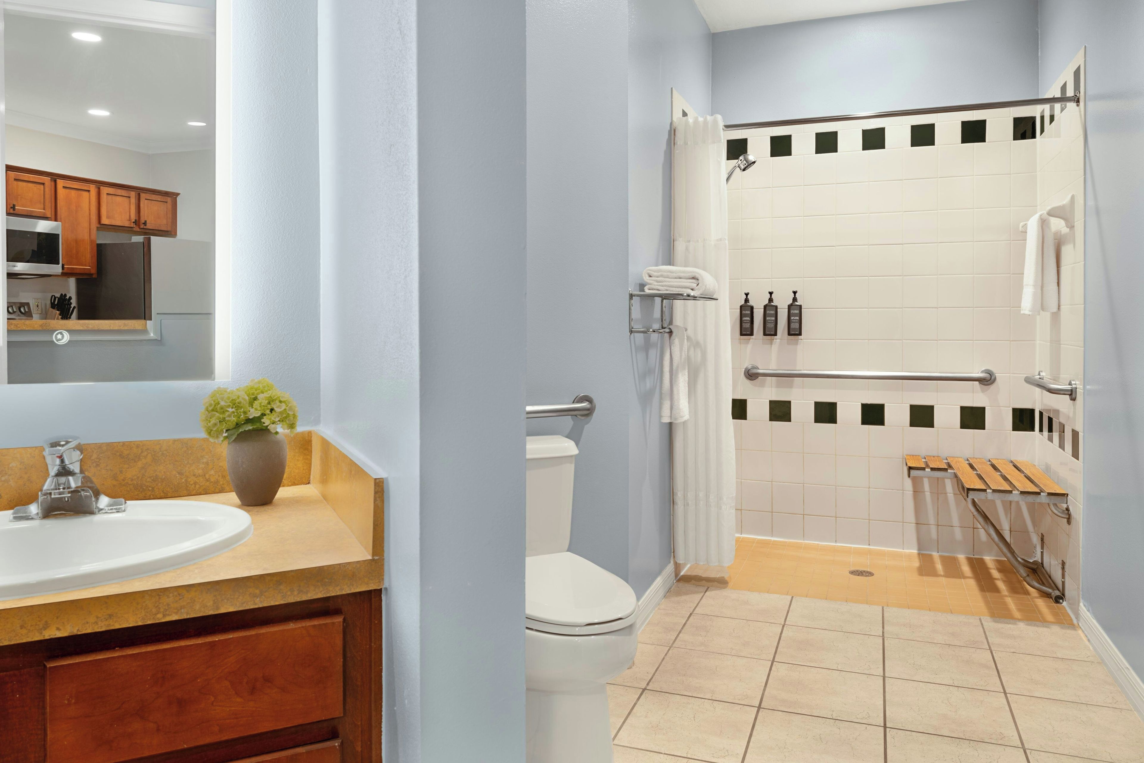 Un baño moderno con lavamanos, inodoro, ducha y banco de madera.