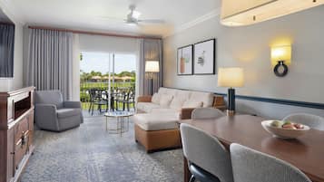 Una habitación de hotel con sofá, sillones, una mesa de comedor y vistas al exterior.
