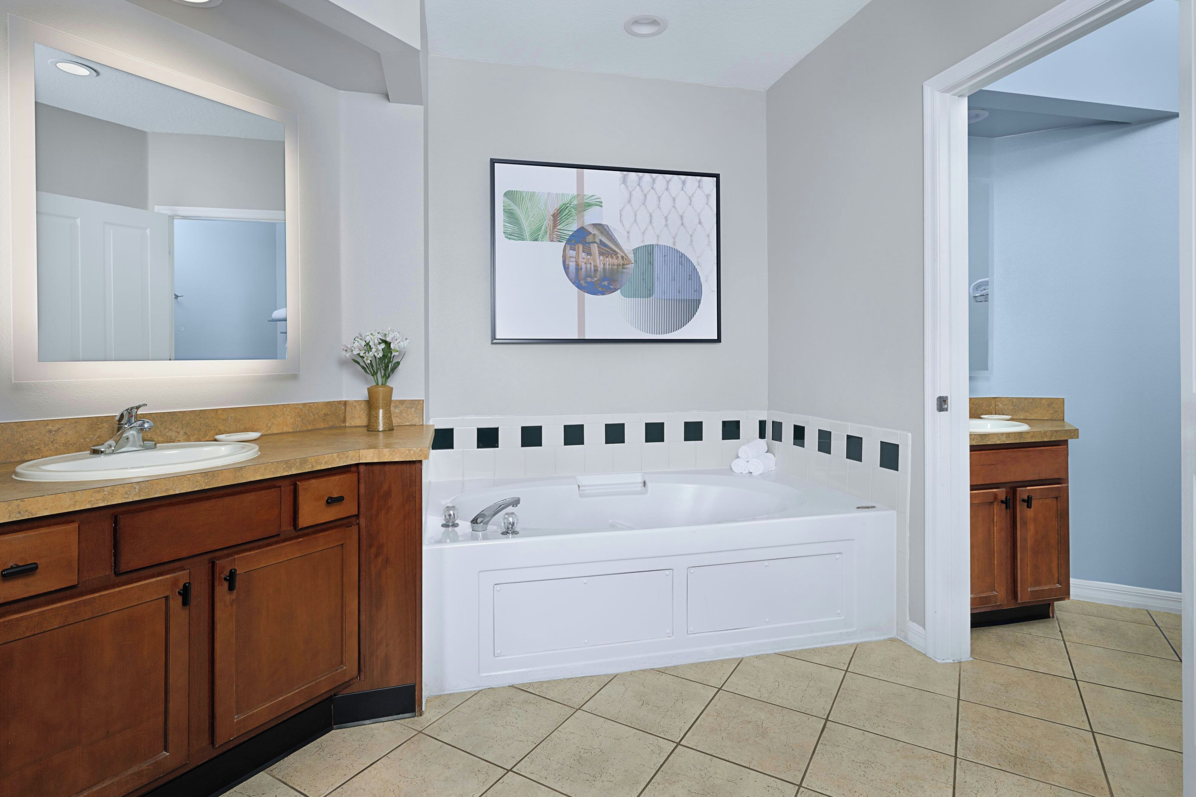 A bathroom with a large mirror, a bathtub, and a sink.