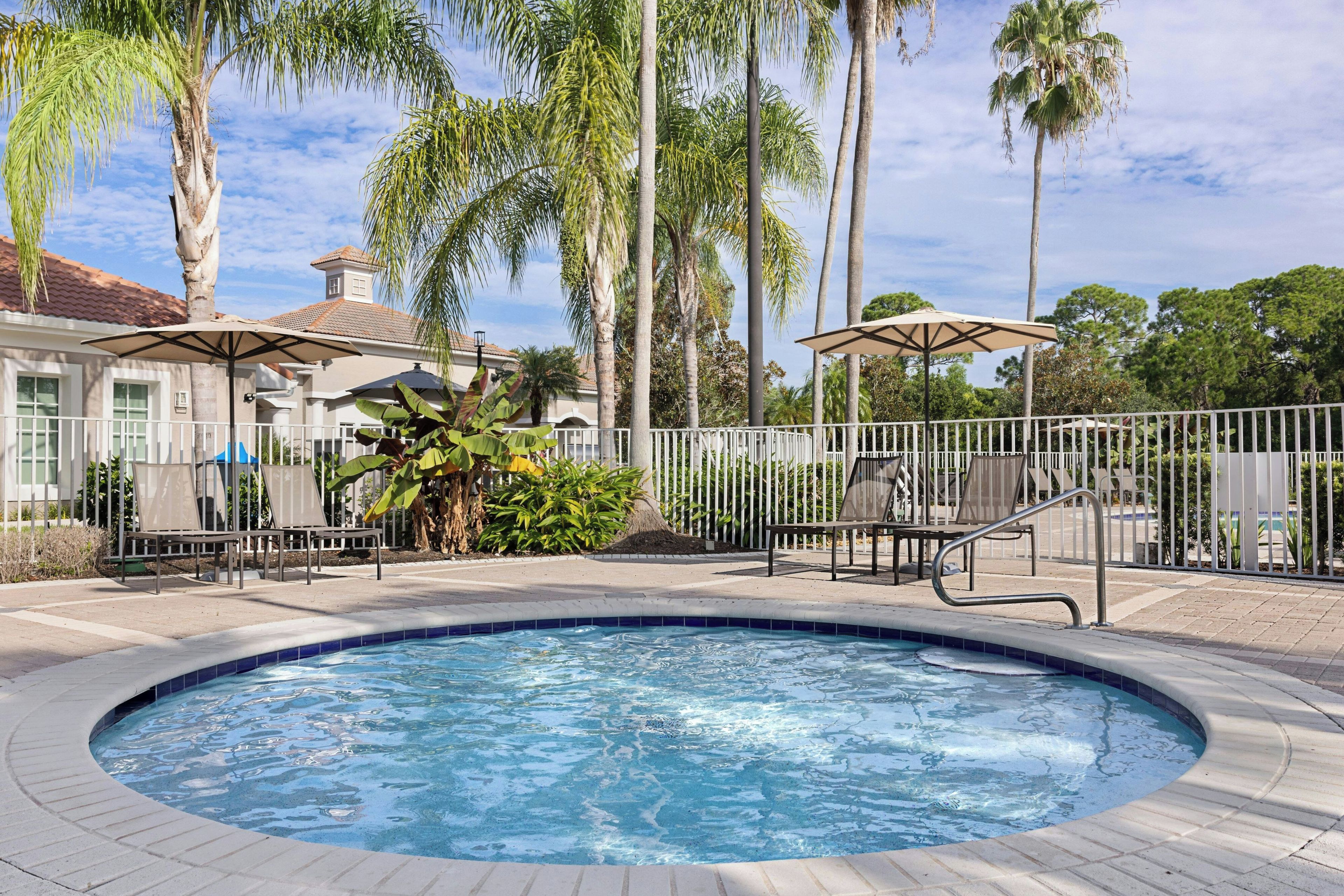 A swimming pool with a surrounding deck, palm trees, and outdoor seating.