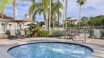 A swimming pool with a surrounding deck, palm trees, and outdoor seating.