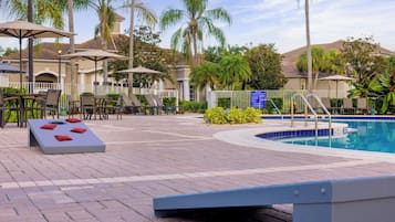 A pool area with lounge chairs, a sunbed, and a pool with a blue tile edge.