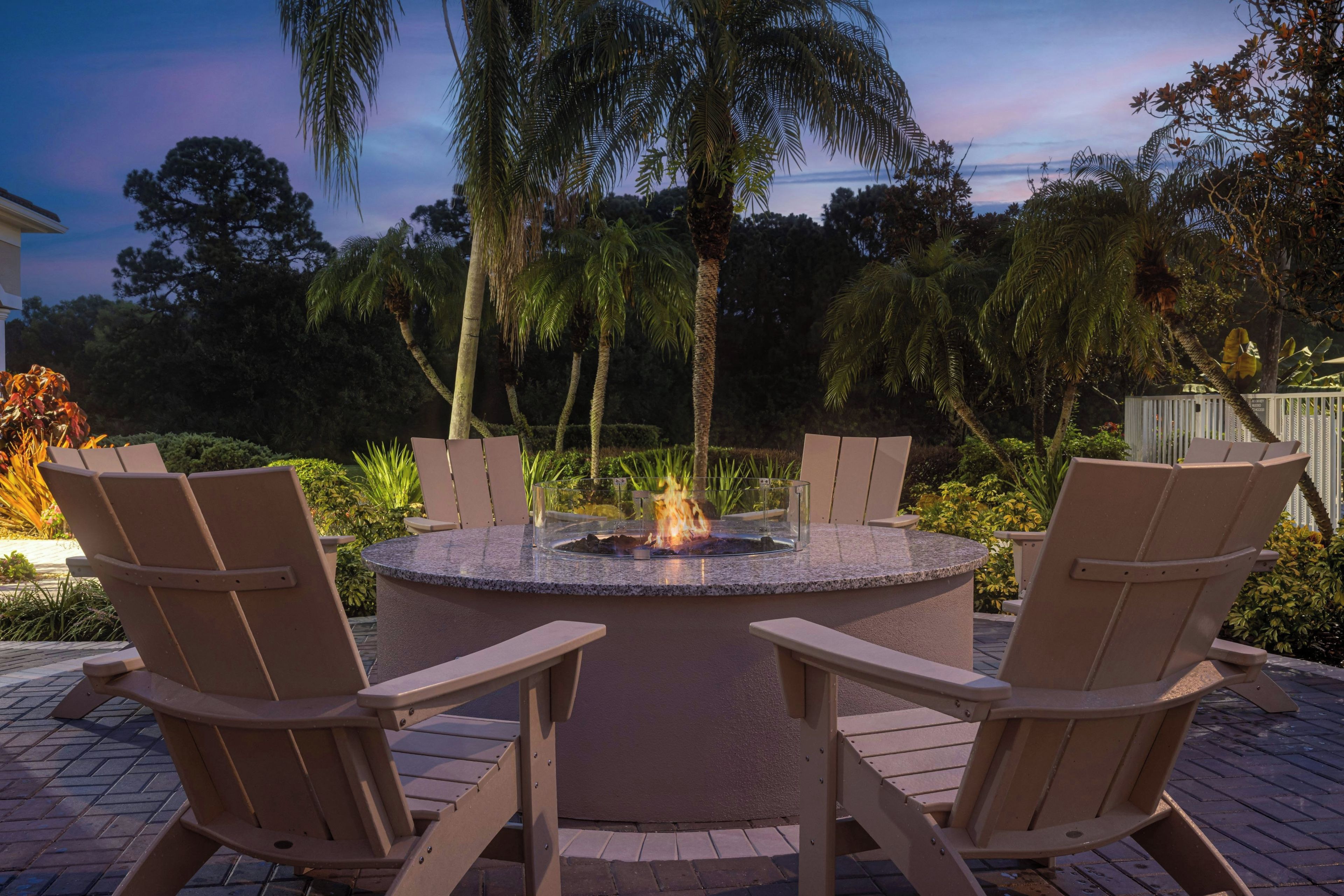 An outdoor seating area with a circular fire pit surrounded by chairs.