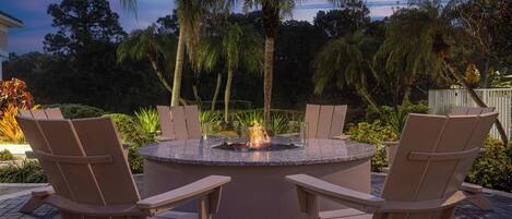 An outdoor seating area with a circular fire pit surrounded by chairs.