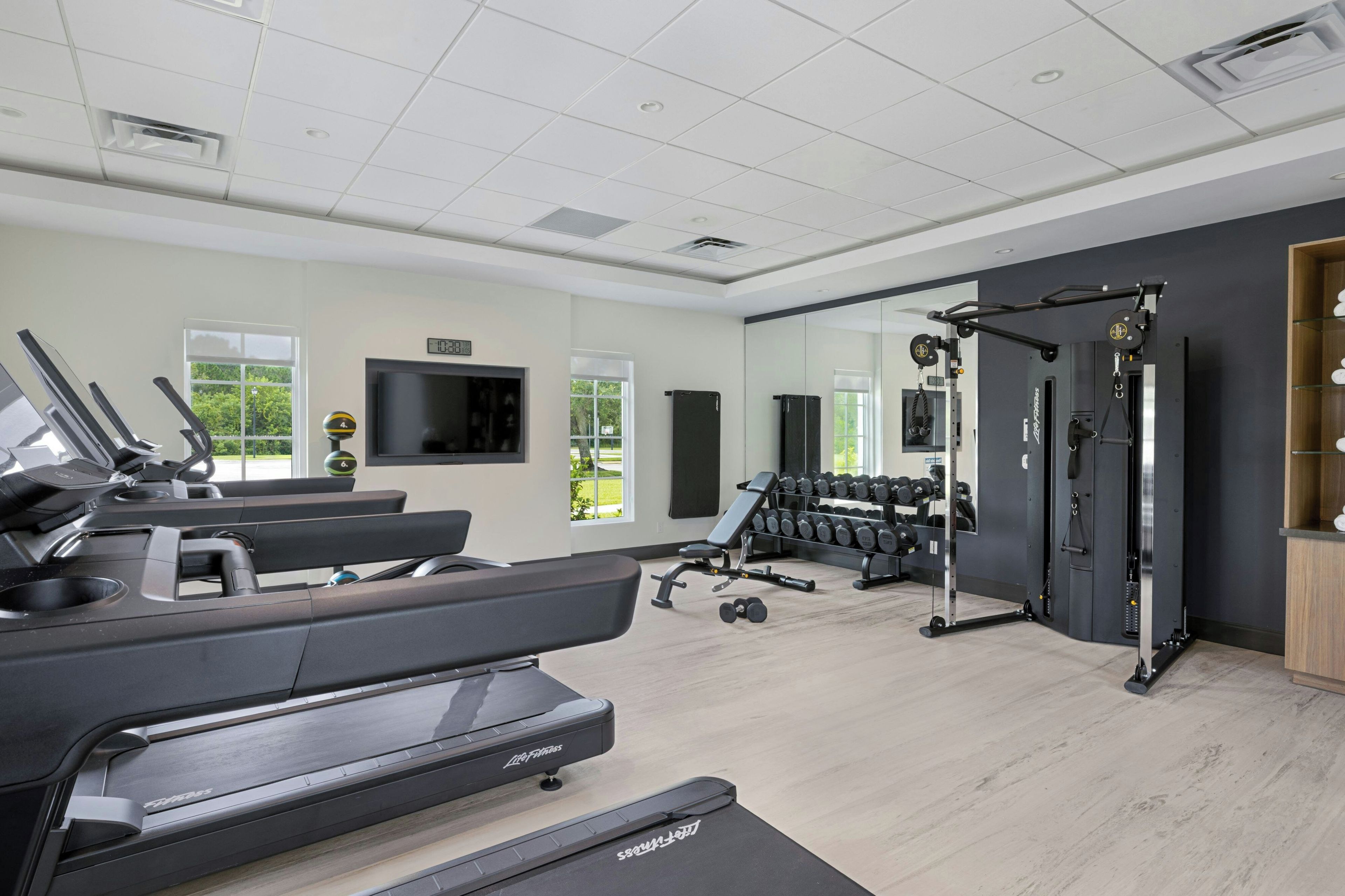 A gym with treadmills, weight machines, and a mirror wall.