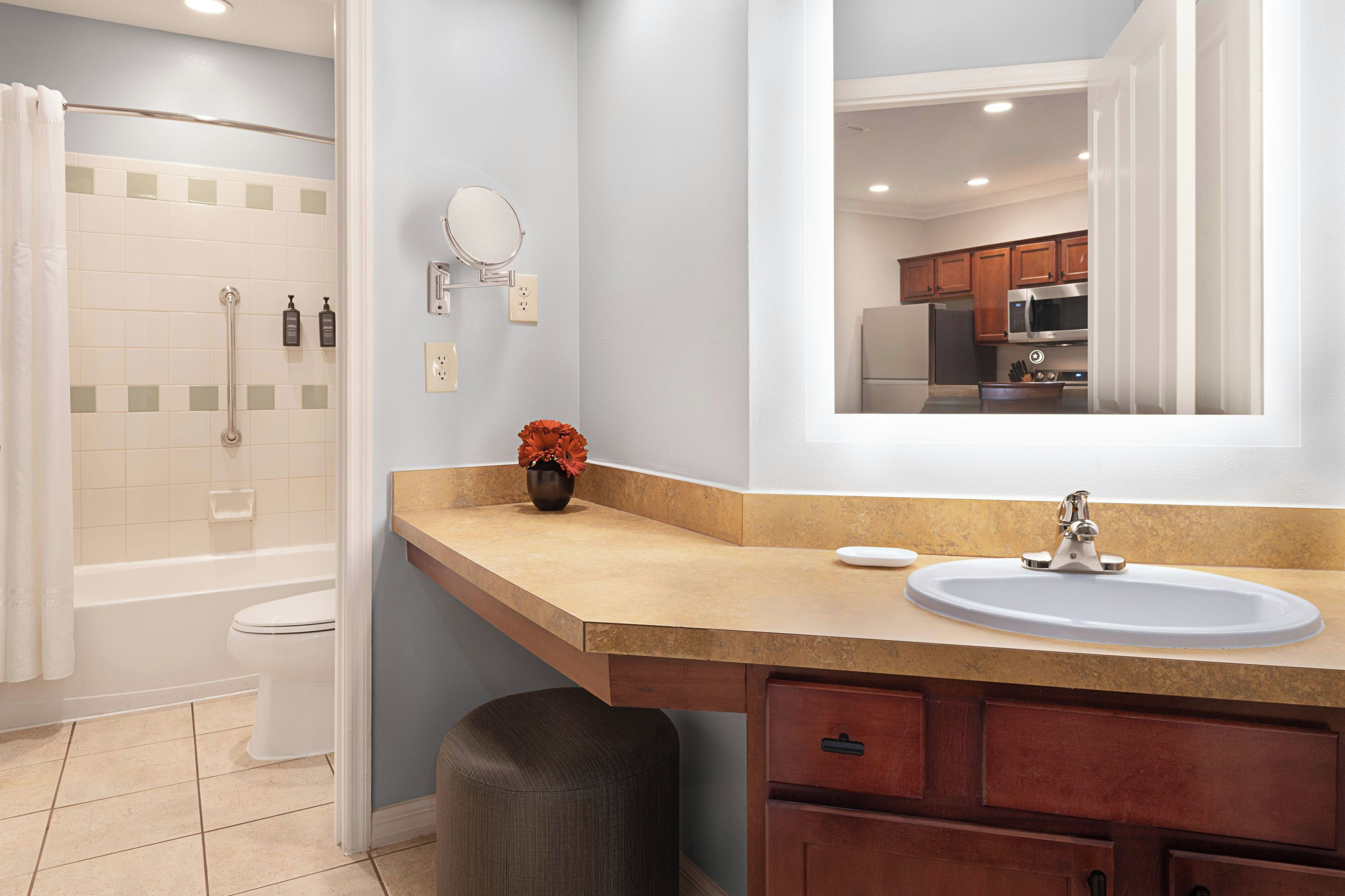 A bathroom with a bathtub, toilet, sink, vanity, and a mirror.