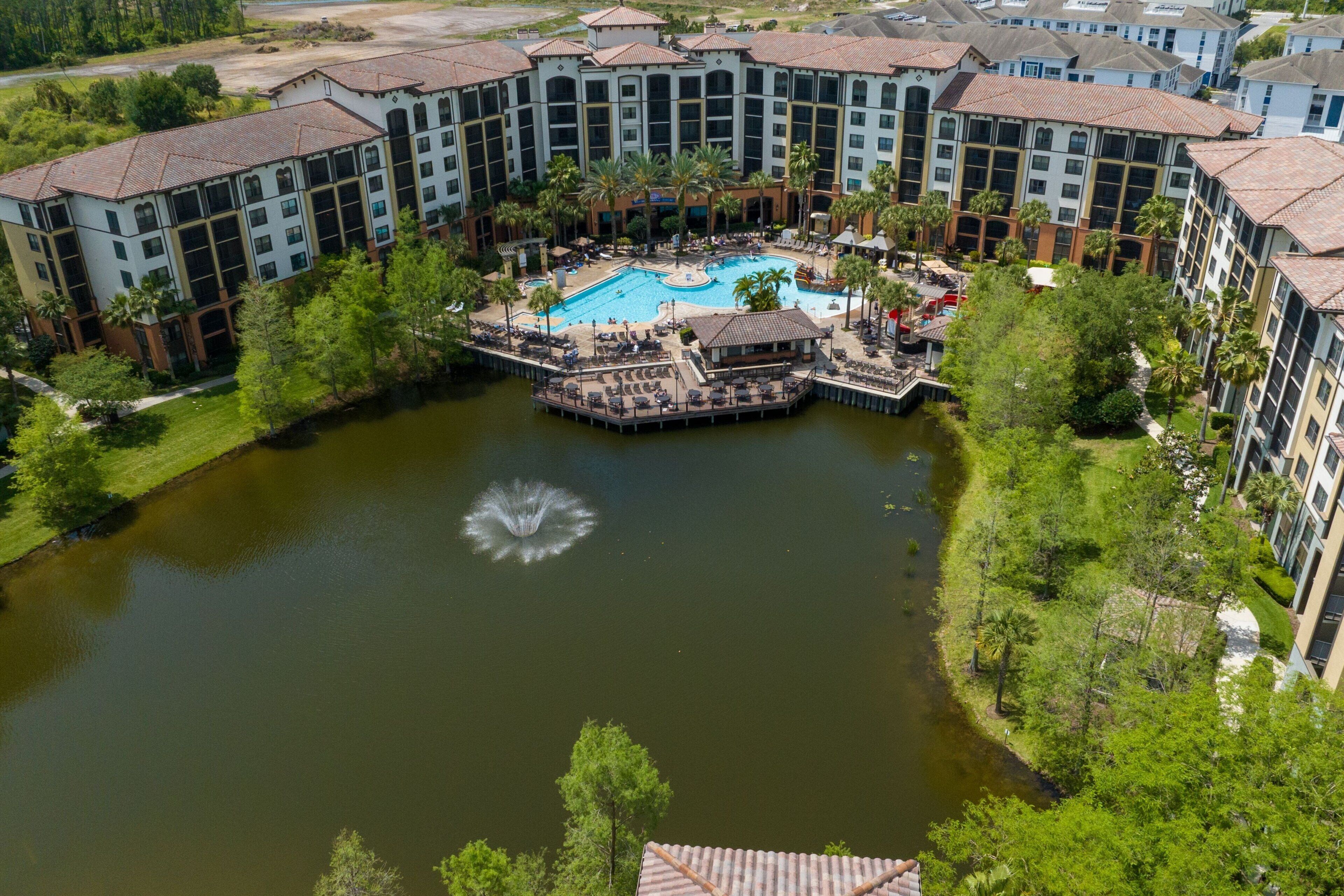 A hotel with a central pool surrounded by lush greenery and a fountain.