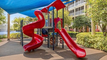 Een speeltuin met rode glijbanen en een blauw dakzeil.