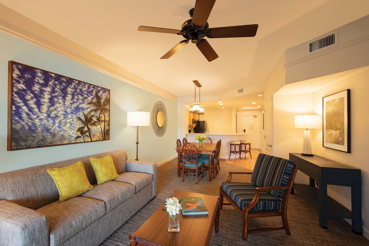 A living room with a sofa, armchairs, a coffee table, and a dining area with chairs and a table.