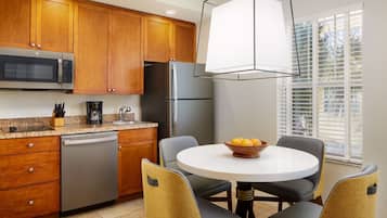 Una cocina moderna con armarios de madera, electrodomésticos de acero inoxidable y una mesa redonda con sillas.