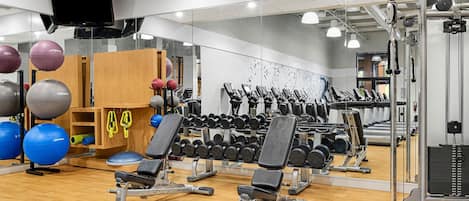 Een sportschool met trainingsapparatuur, een televisie en een spiegel.