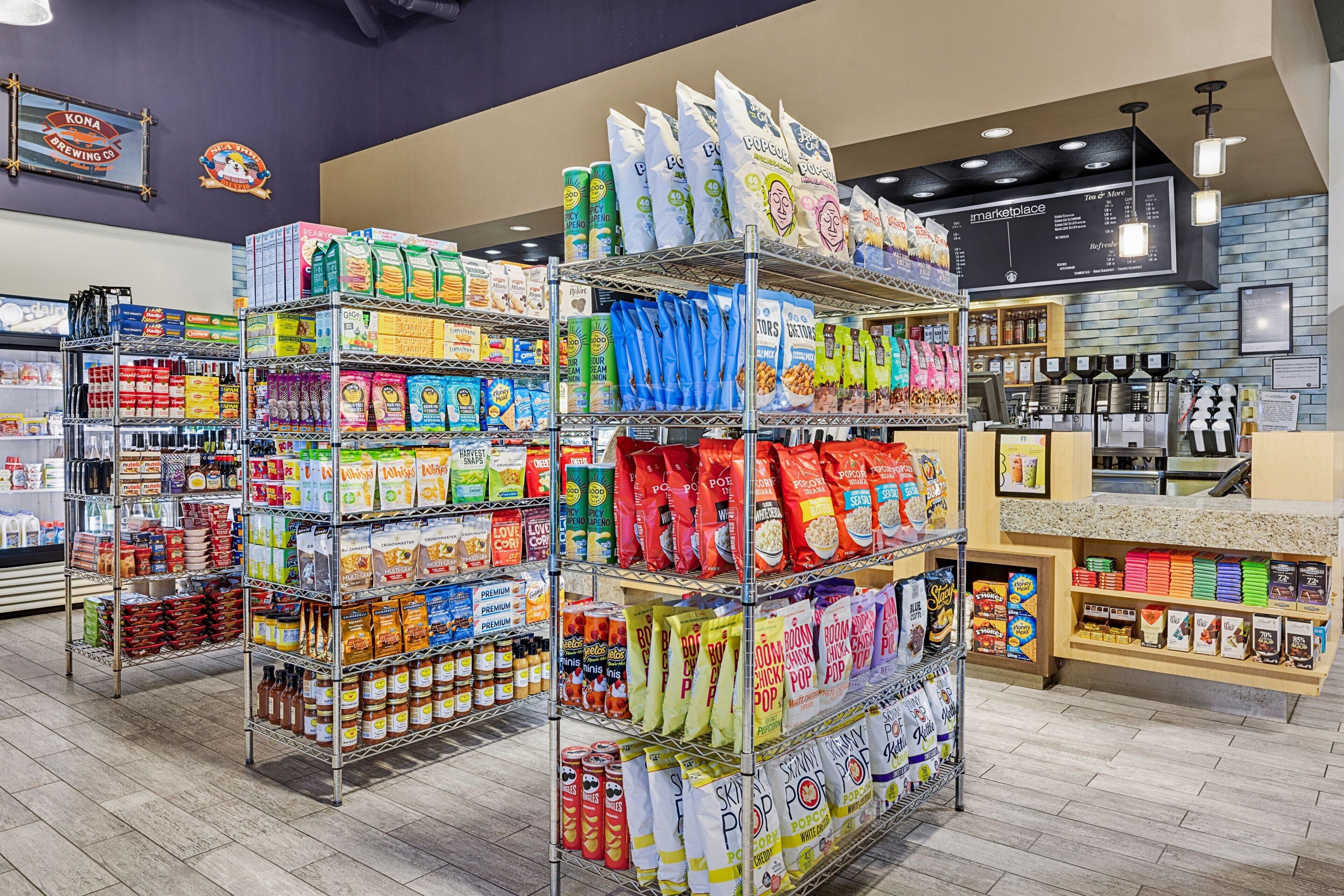 Een supermarkt met schappen vol met verschillende etenswaren en een koffiehoek op de achtergrond.