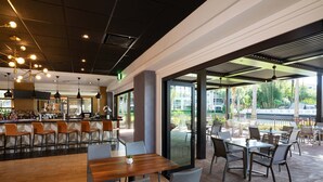 A modern restaurant with a bar area, outdoor seating, and a view of the outdoors.