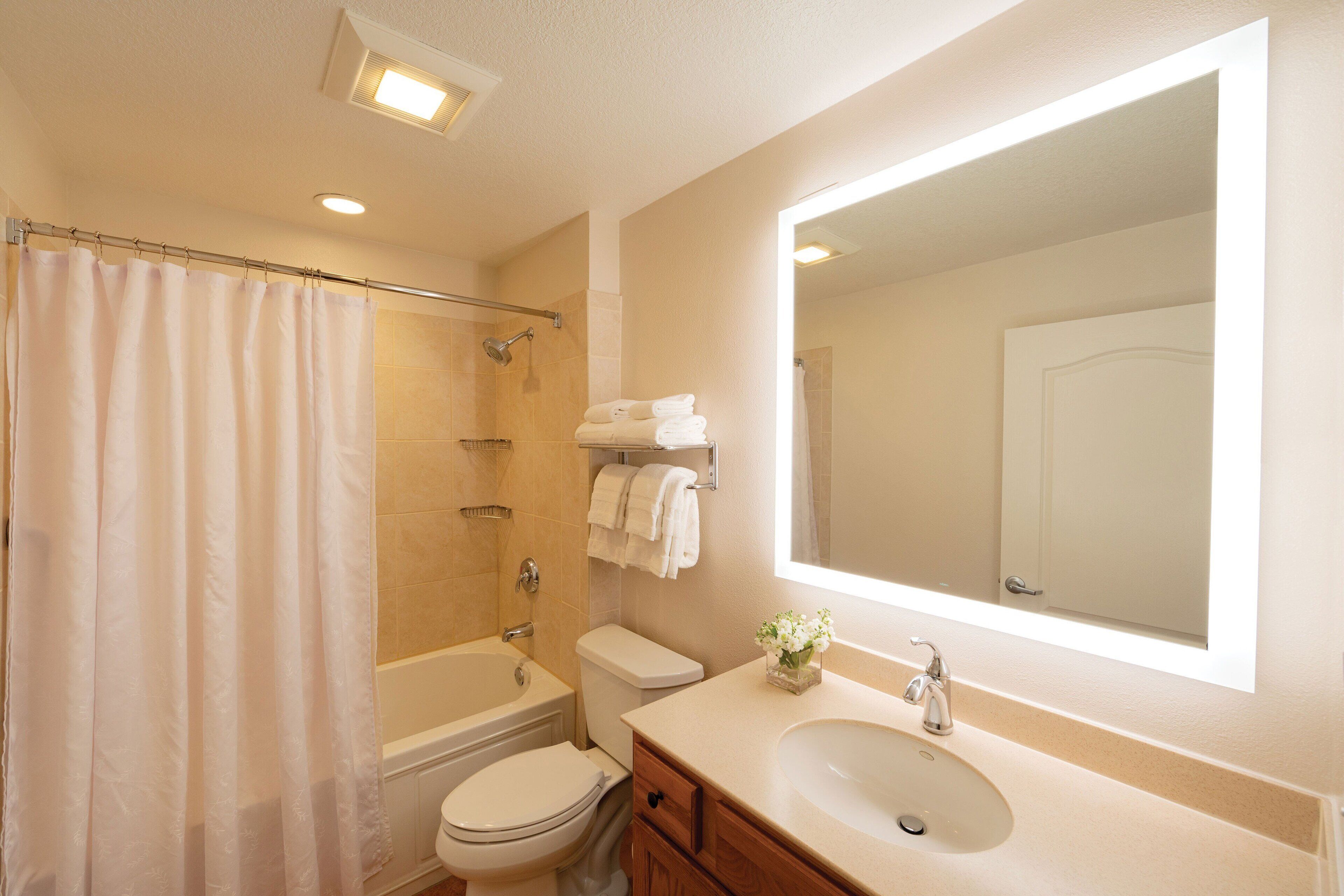 A bathroom with a bathtub, toilet, sink, and a large mirror.