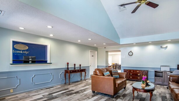 Un vestíbulo amplio con una decoración azul y blanca, que incluye un sofá de cuero, una mesa de centro de madera y un mostrador de recepción.