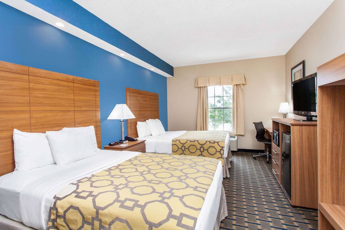 Une chambre d’hôtel avec deux lits, un bureau, une télévision et un minibar.