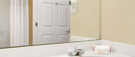 A bathroom with a white sink, a mirror, a towel rack, and a shower curtain.