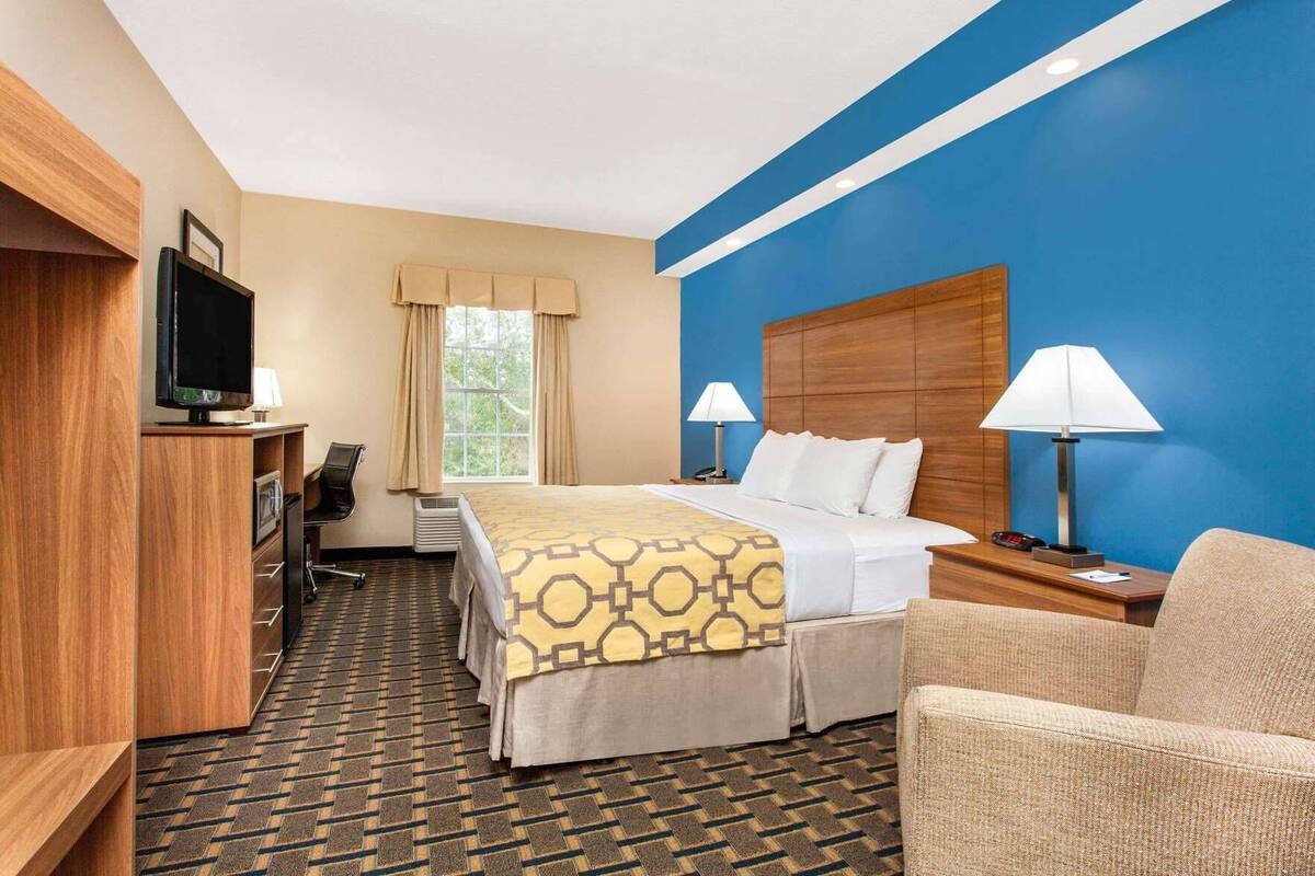 Une chambre d’hôtel comprenant un lit, deux lampes de chevet, une télévision, un bureau et une chaise.