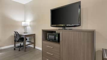 A hotel room with a flat-screen TV, a microwave, a desk with a chair, and a lamp.