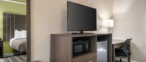 A hotel room with a bed, a desk with a chair, a television, a microwave, and a refrigerator.