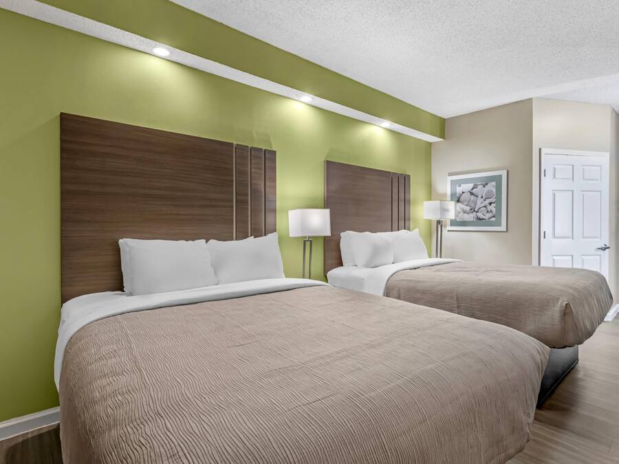 Una habitación de hotel con dos camas, una pared verde y una puerta.