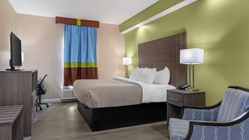 Una camera d'albergo con un letto, lampade sui comodini, una scrivania con un computer, una sedia e una televisione.
