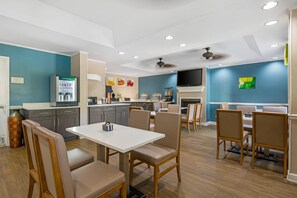 A modern kitchen with a dining area, equipped with a refrigerator, microwave, and a flat-screen TV. - Quality Inn Ormond Beach – Daytona (Ormond Beach)