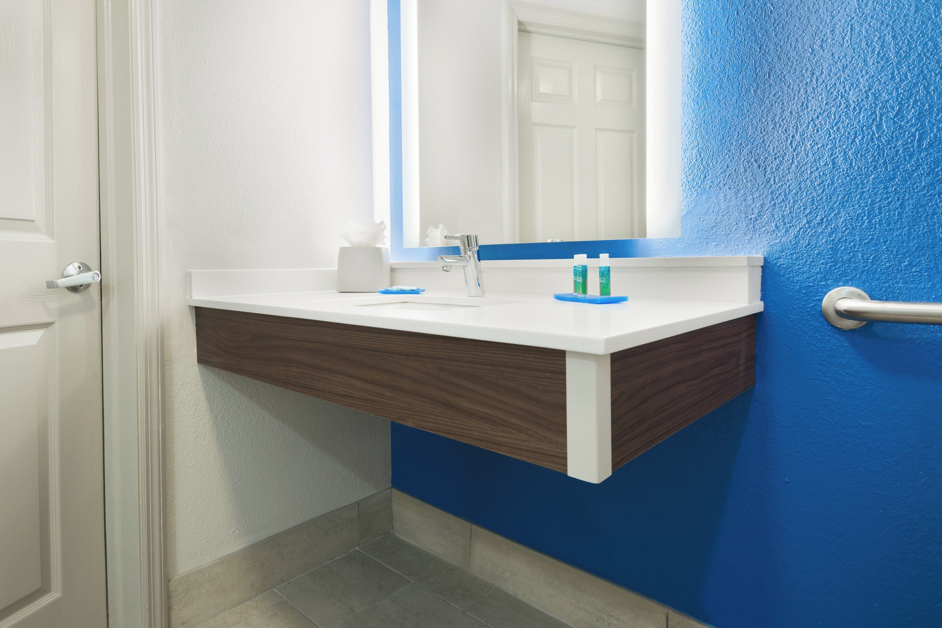 Ein Badezimmer mit einem weißen Waschbecken, einem Spiegel und einer blauen Wand.