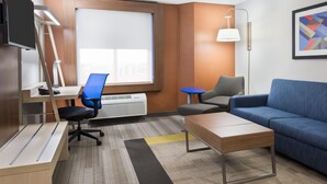 A modern hotel room with a desk, chair, sofa, and a large window. - Holiday Inn Express & Suites Nearest Universal Orlando by IHG (Orlando)