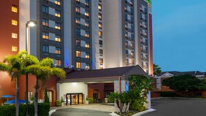 A multi-story hotel with a modern design, featuring a well-lit entrance and a parking area. - Holiday Inn Express & Suites Nearest Universal Orlando by IHG (Orlando)