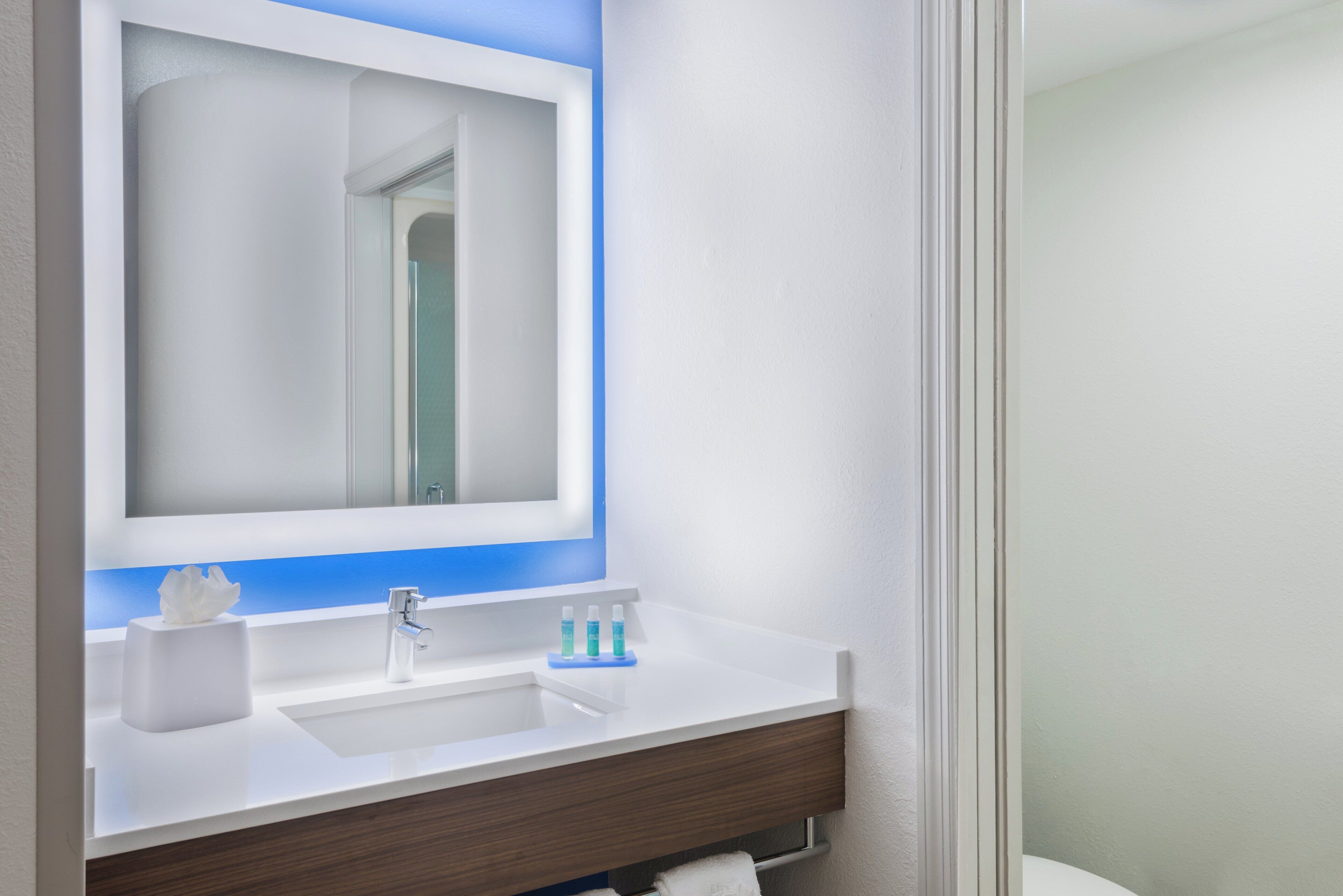 A bathroom with a white sink, a mirror, and a blue accent strip.