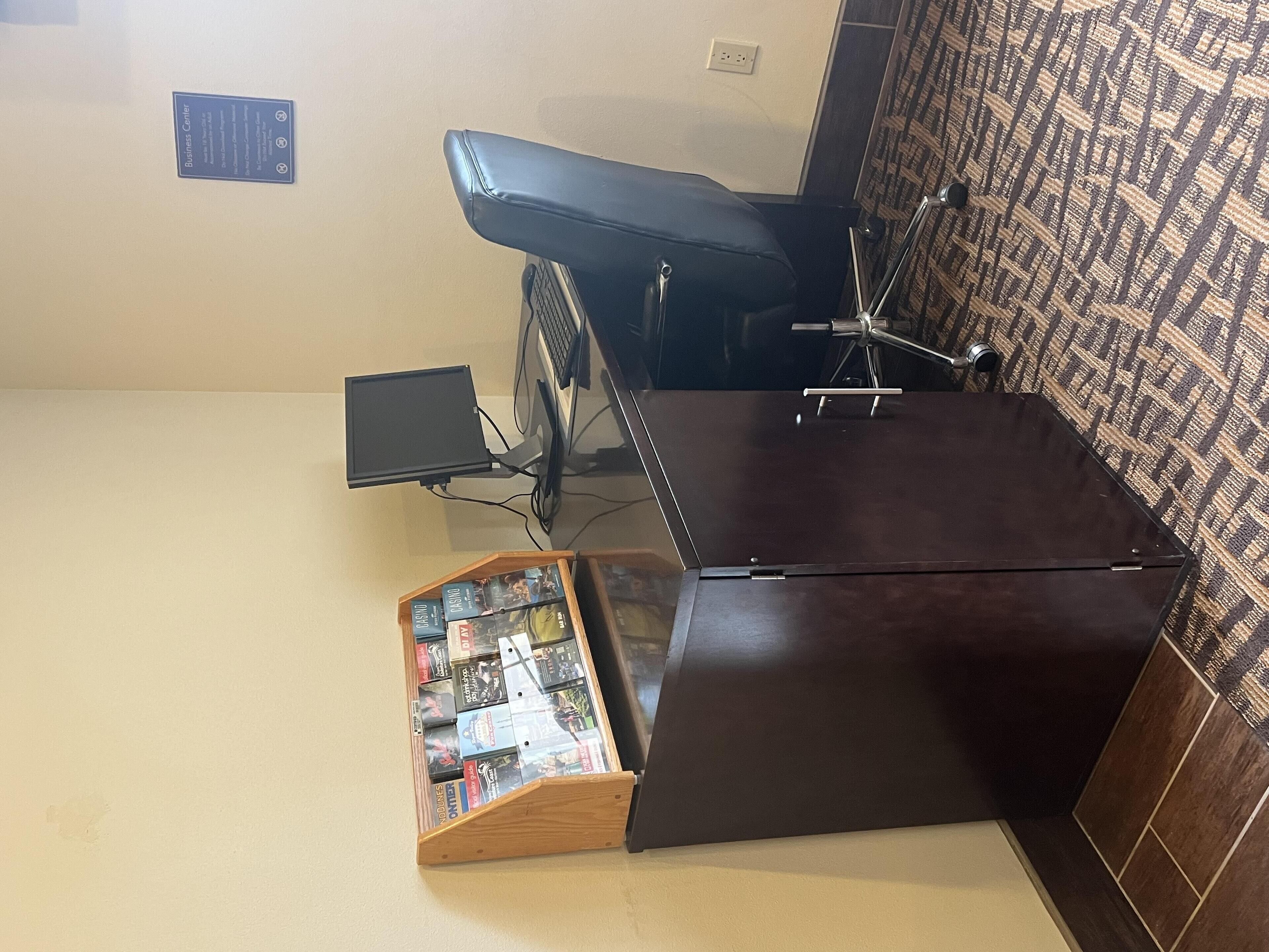 A room with a desk, a chair, a computer, and a small wooden display case with items.