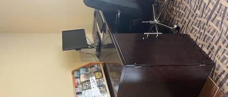 A room with a desk, a chair, a computer, and a small wooden display case with items.