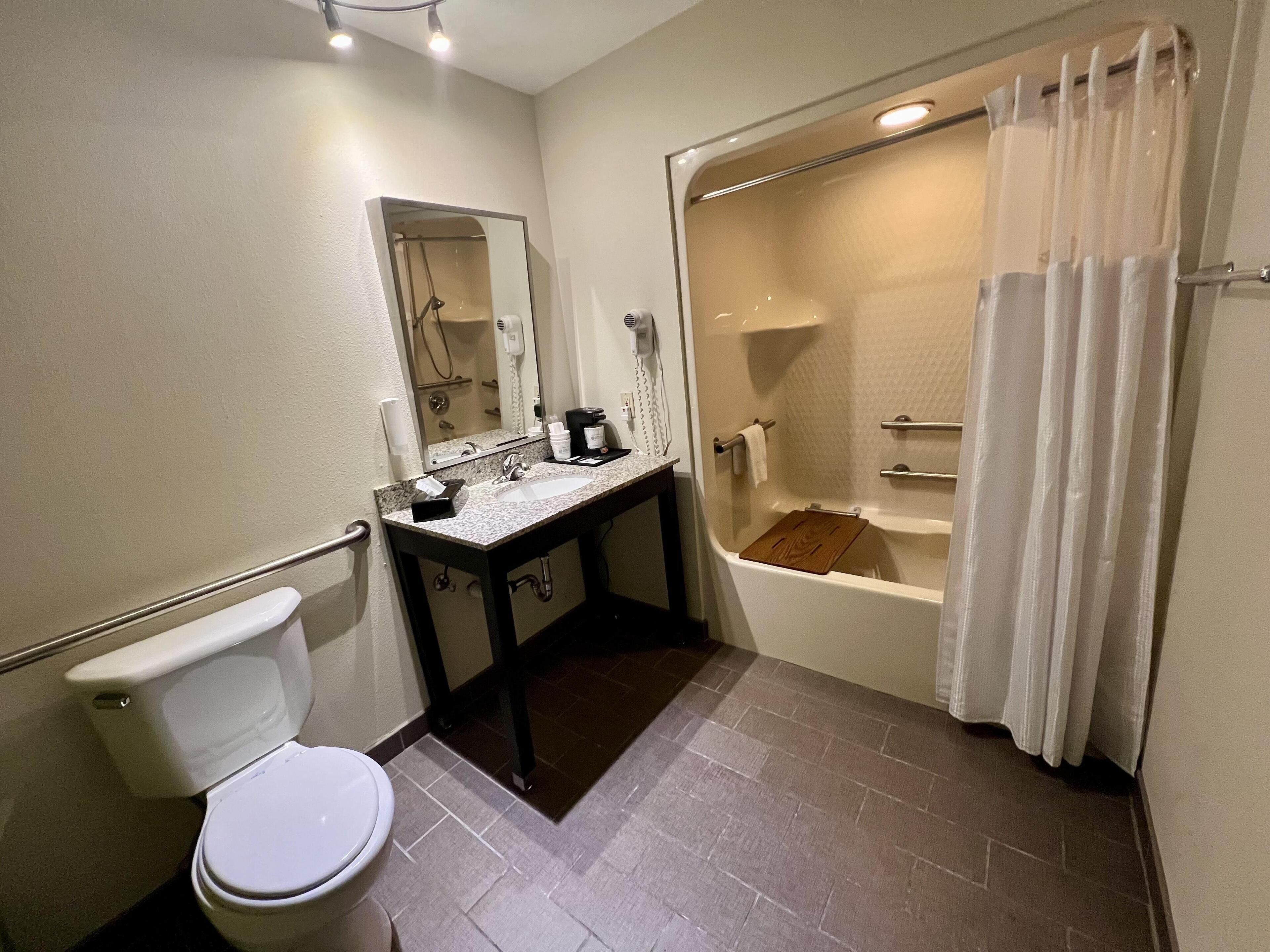 A bathroom with a toilet, sink, mirror, and bathtub.