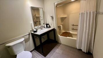 A bathroom with a toilet, sink, mirror, and bathtub.