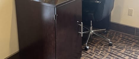 A reception desk with a computer, a chair, and a magazine rack.