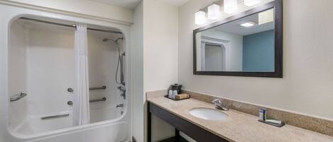 A bathroom with a bathtub, a sink, and a mirror.