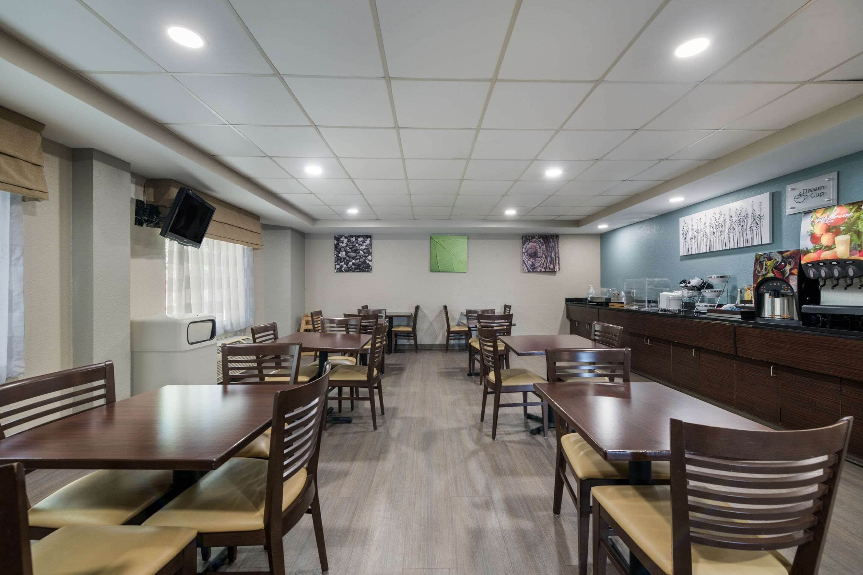 A restaurant with multiple tables and chairs, a counter with a coffee machine, and artwork on the walls.