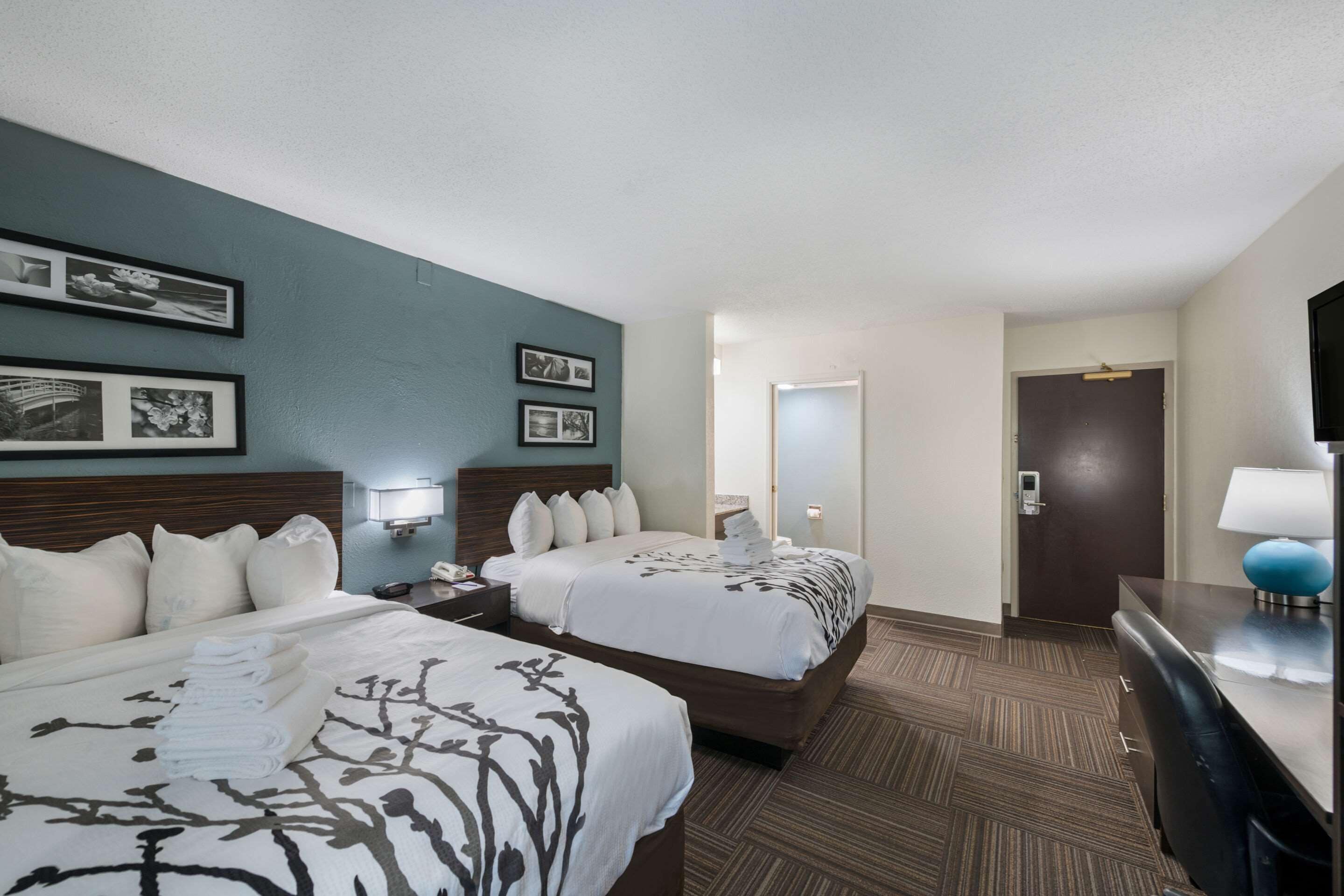 Quarto de hotel com duas camas, uma escrivaninha e um espelho.