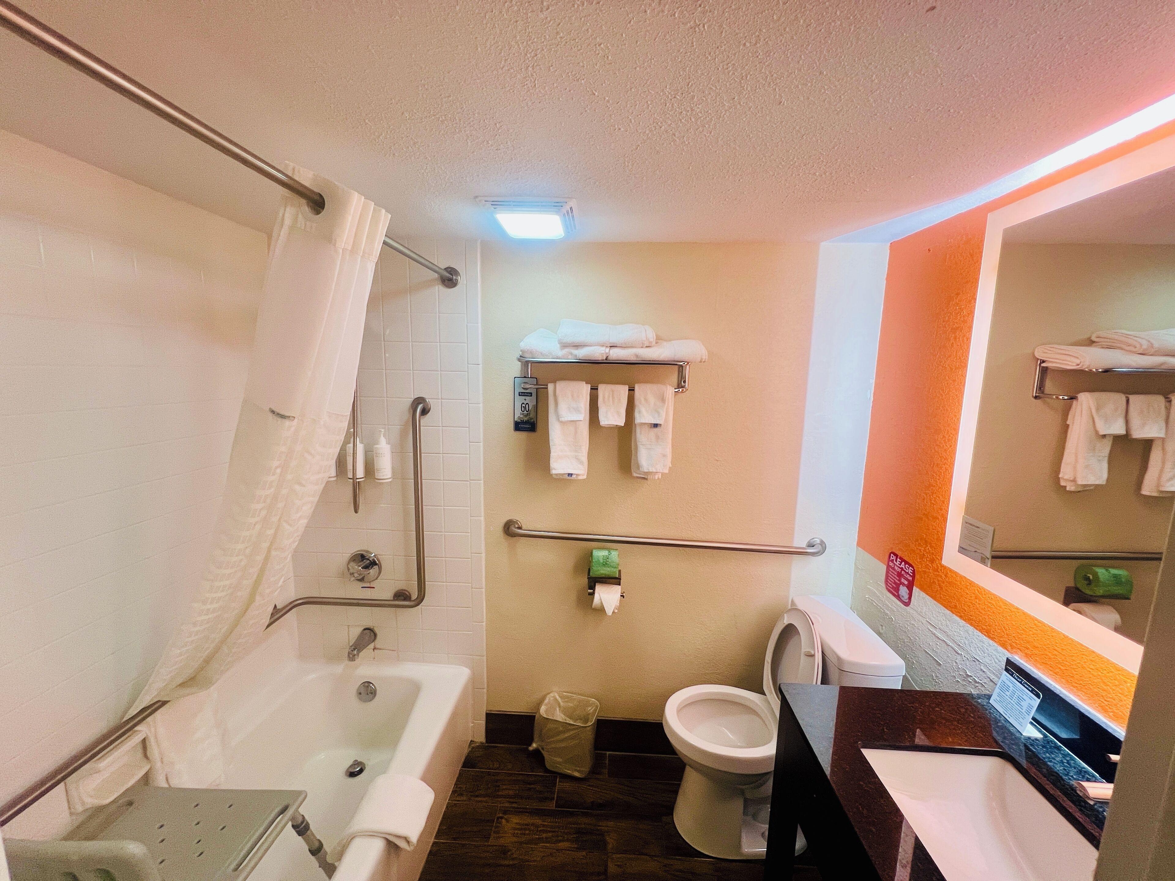 A bathroom with a bathtub, toilet, and sink. There are towels and toiletries visible.