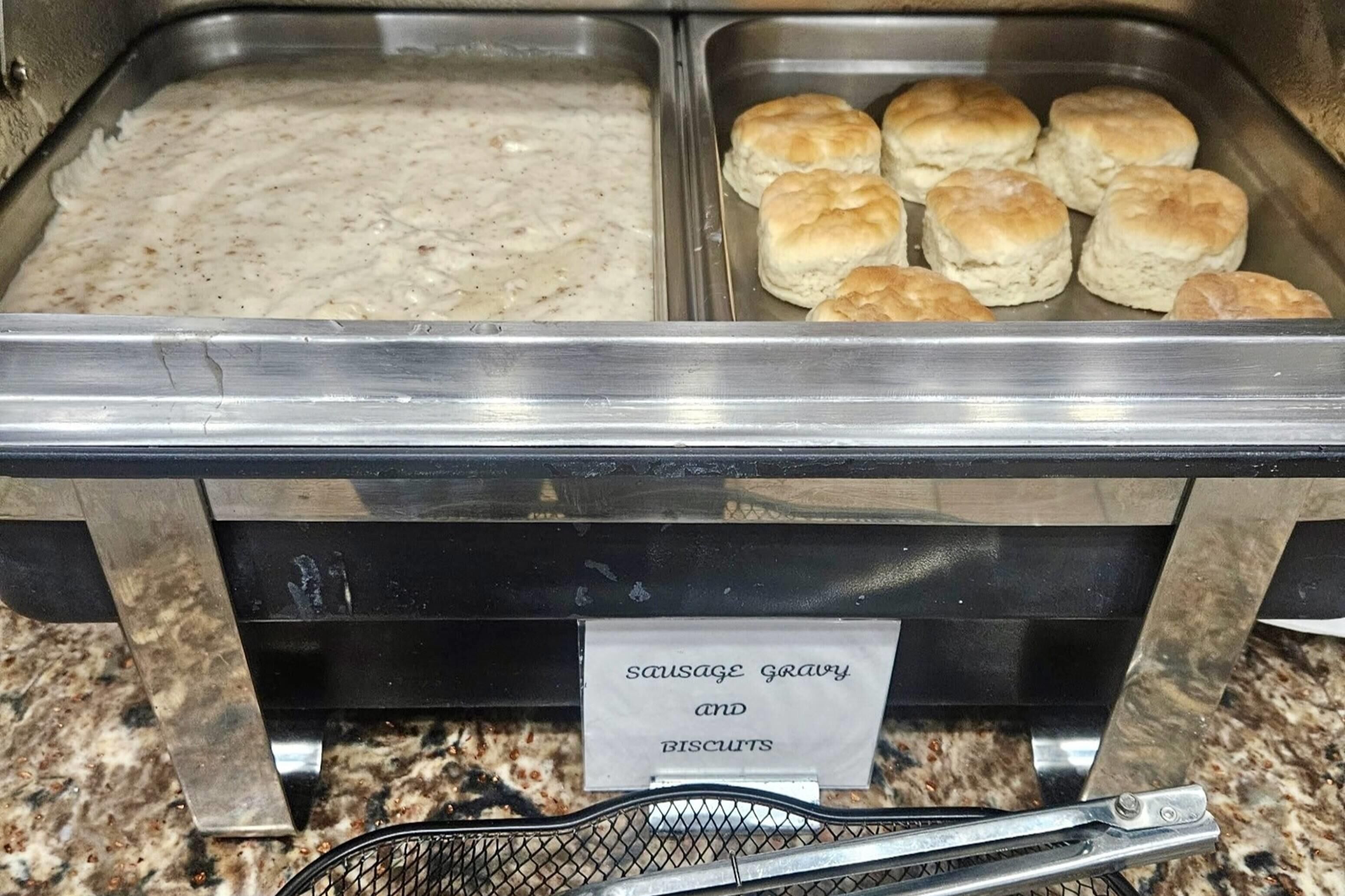 A buffet with a sign indicating sausage gravy and biscuits.
