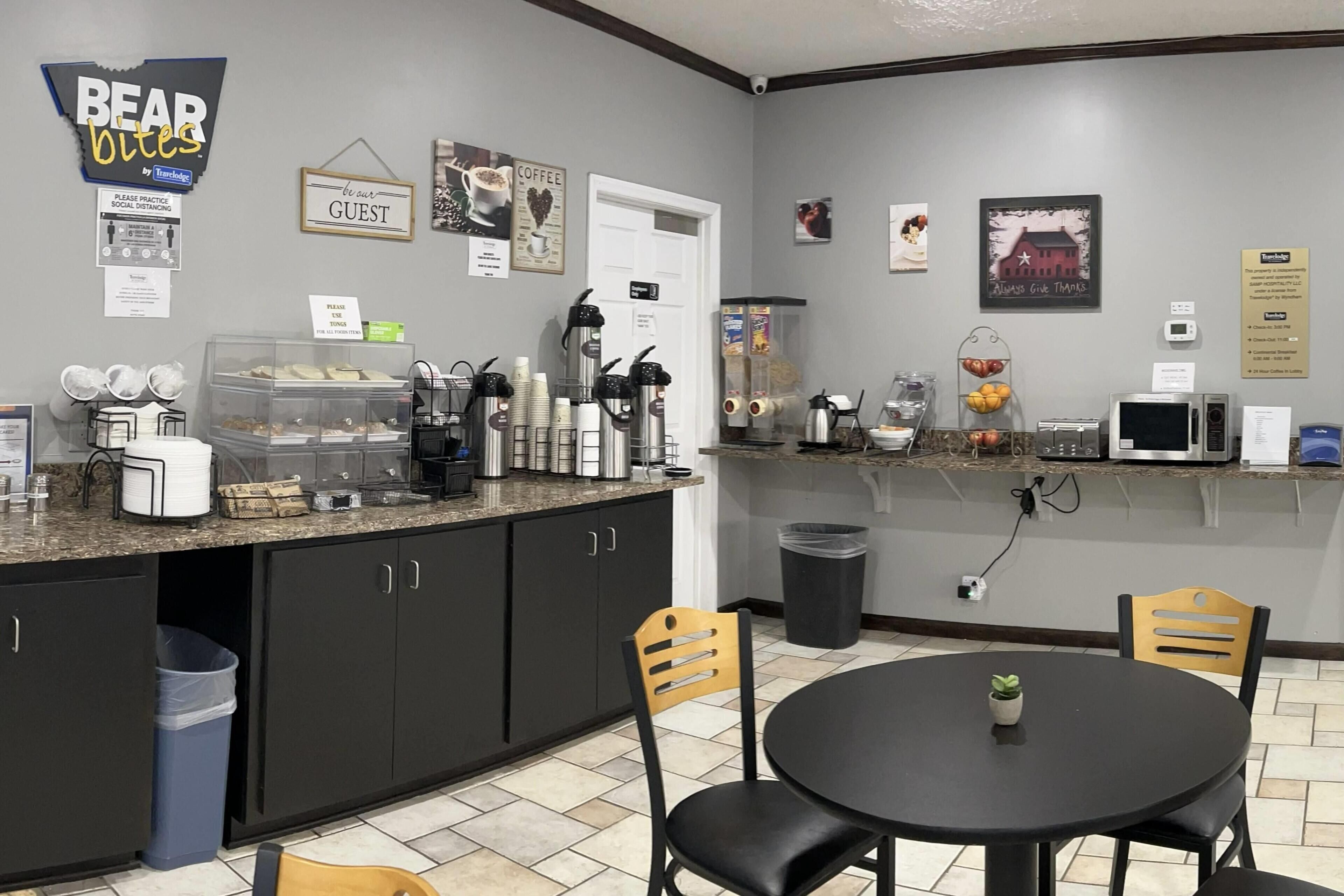 A kitchen area with a coffee station, a trash bin, and a small table with a plant.
