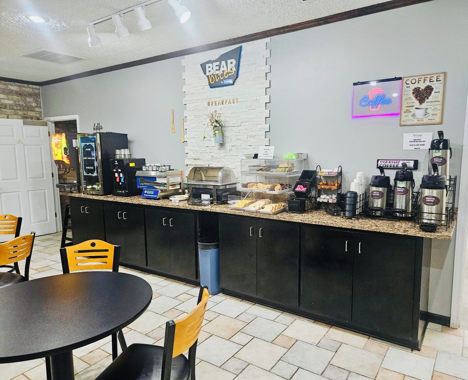 A breakfast area with a counter displaying coffee machines, a sign for 'BEAR OUIES', and a 'Coffee' neon sign.