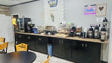 A breakfast area with a counter displaying coffee machines, a sign for 'BEAR OUIES', and a 'Coffee' neon sign.