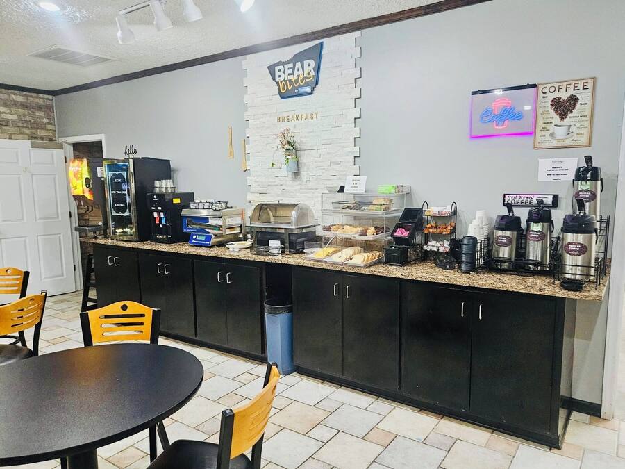 A breakfast area with a counter displaying coffee machines, a sign for 'BEAR OUIES', and a 'Coffee' neon sign.