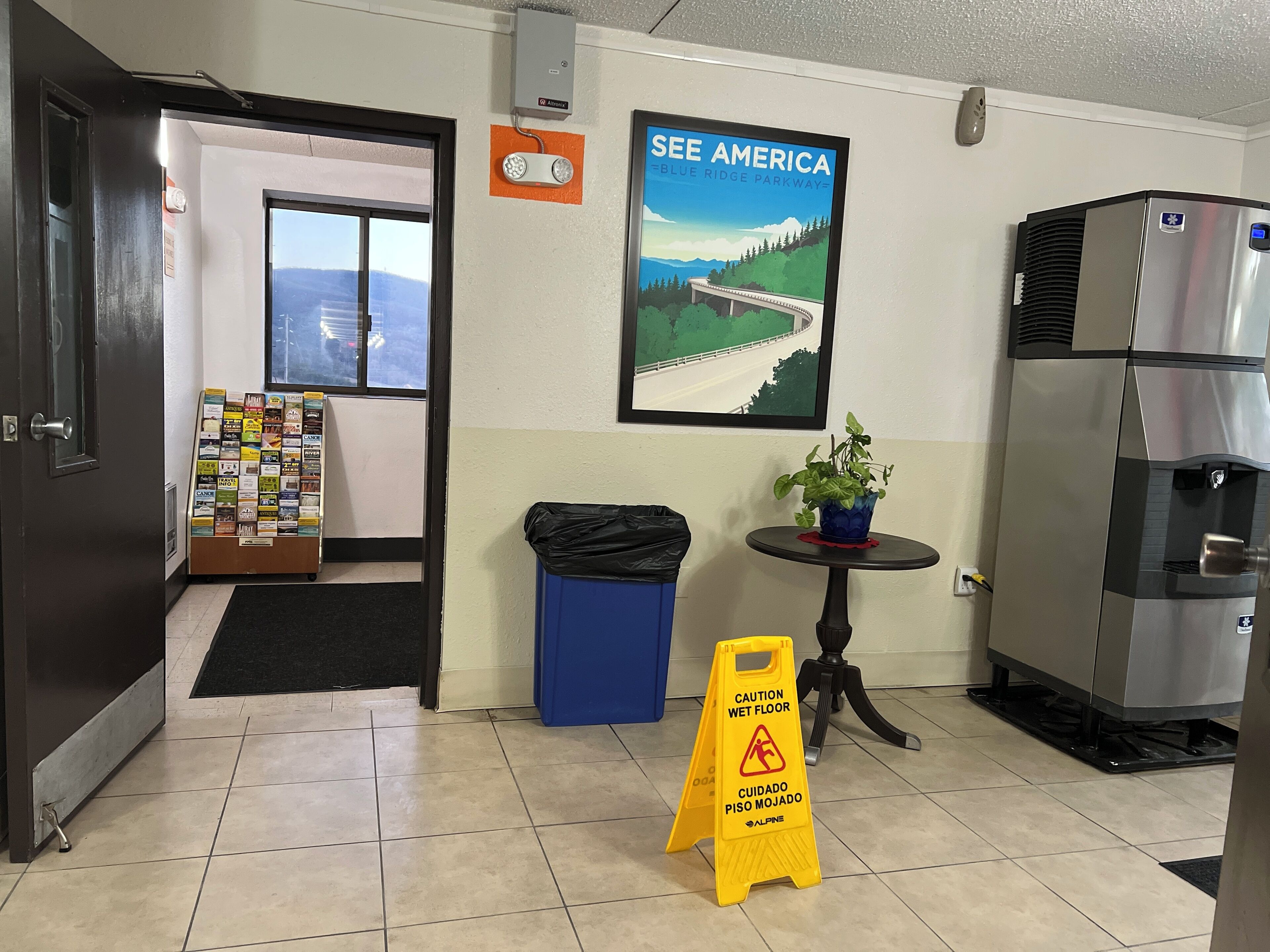 Eine Hottelevhalle mit einer Rezeption, einem Poster der Blue Ridge Parkway, einem Wasserspender und einem Warnschild auf dem Boden.