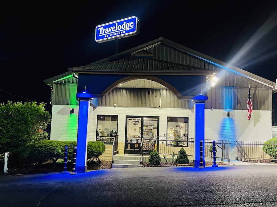 A Travelodge by Wyndham with a prominent sign, a covered entrance, and a small American flag.