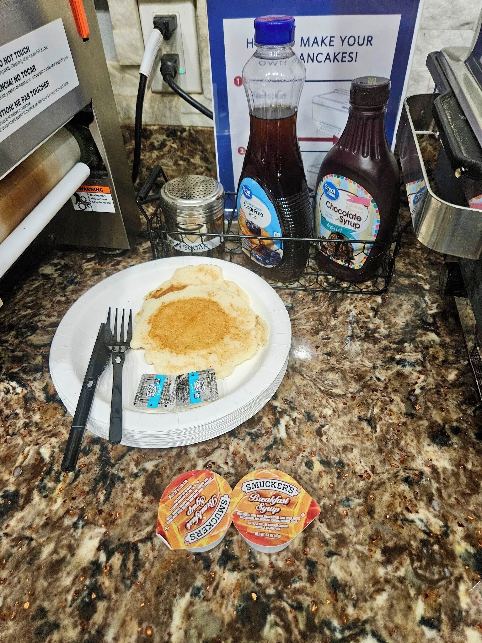 Un plato de desayuno con panqueques, un tenedor y dos sobres de almíbar.