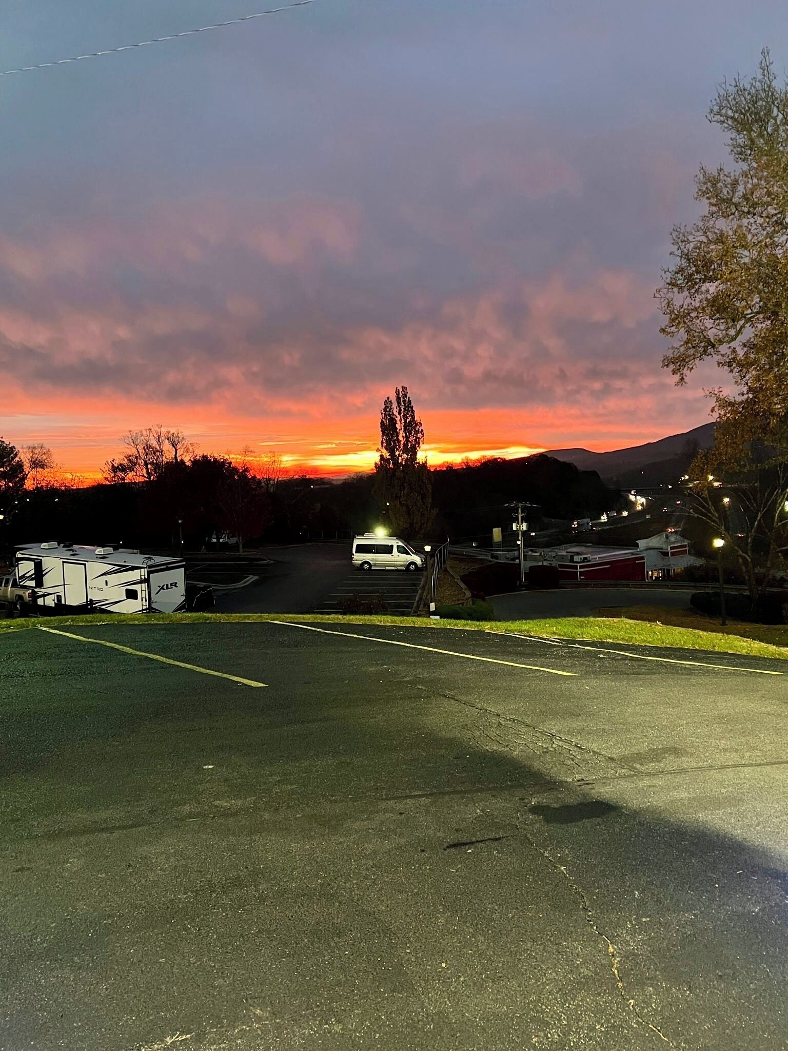 A parking lot with a white van and a camper trailer.